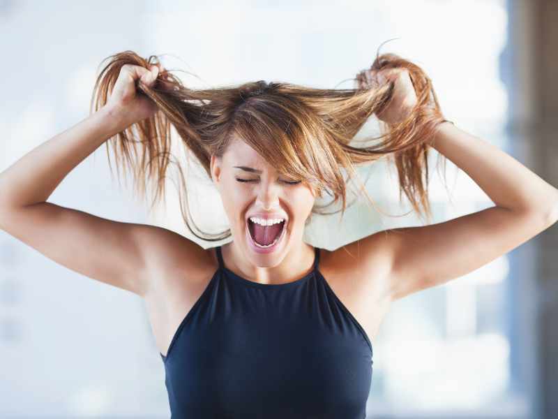 Femme tirant ses cheveux en signe de frustration.