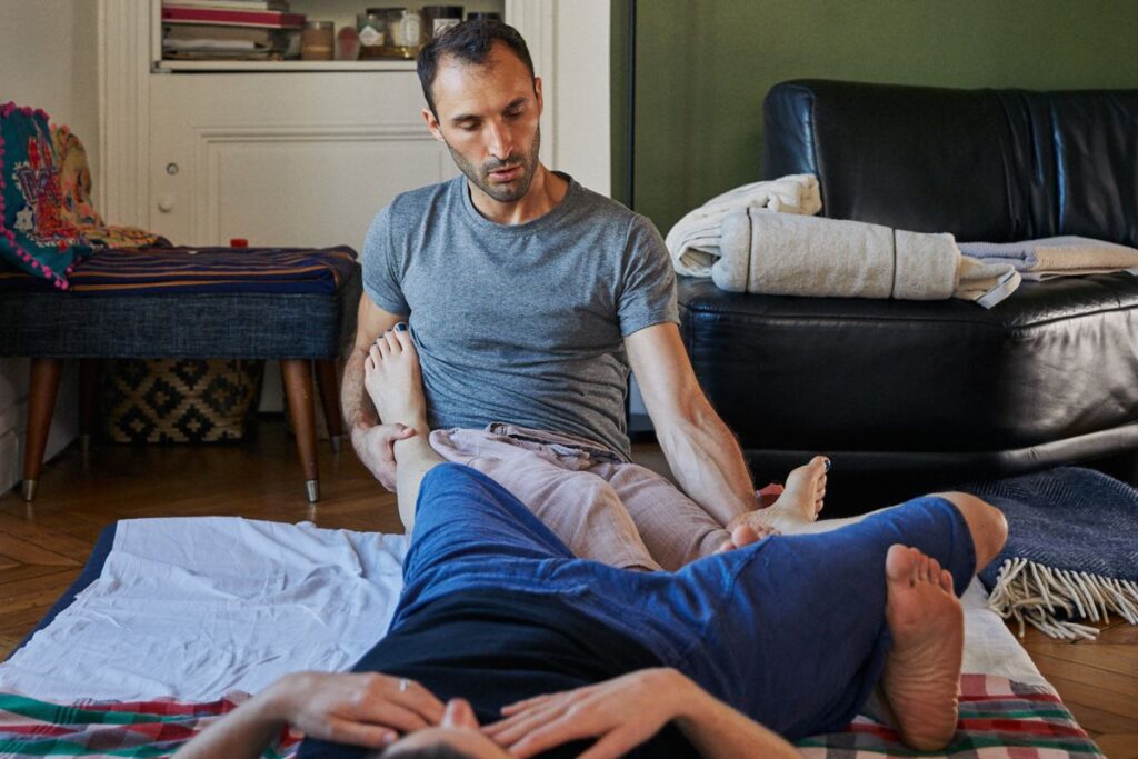 Homme pratiquant massage des pieds à domicile.