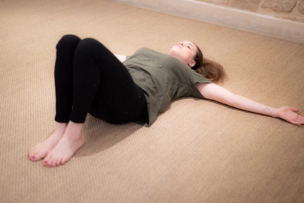 Personne pratiquant un mouvement fluide de MUNZ FLOOR sur un tapis beige, illustrant un cours en ligne.