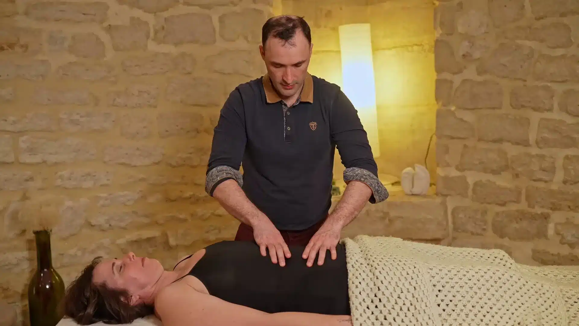 Le fasciathérapeute pose les deux mains sur le buste pendant une séance